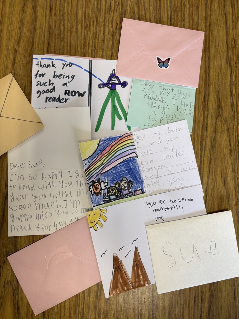 A collection of handmade student thank-you notes, drawings, and envelopes arranged on a classroom table