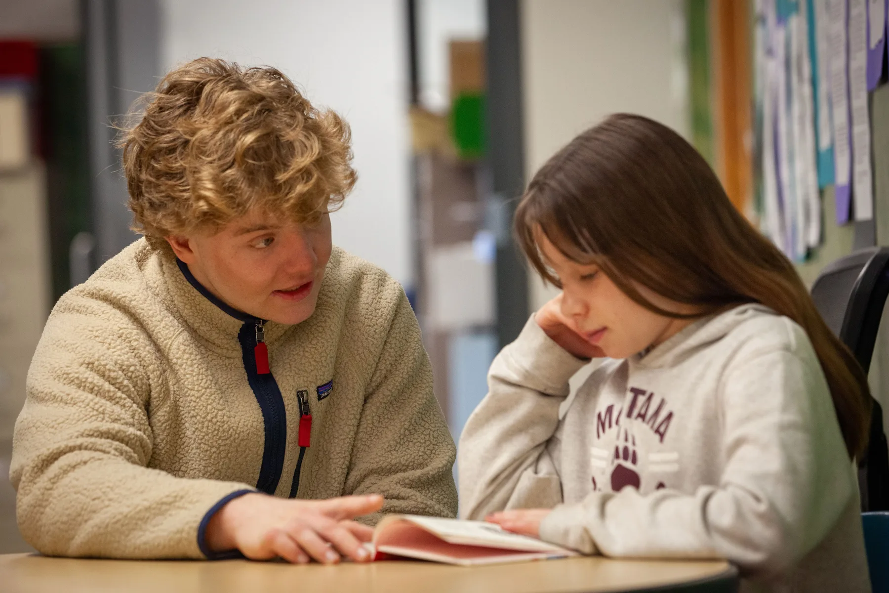 A teen volunteer reading with a student